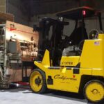 Hyster forklift lifting a large metal container